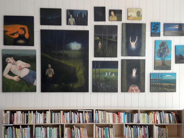 W dolnej części niski regał z książkami, powyżej fragment wystawy malarstwa.
