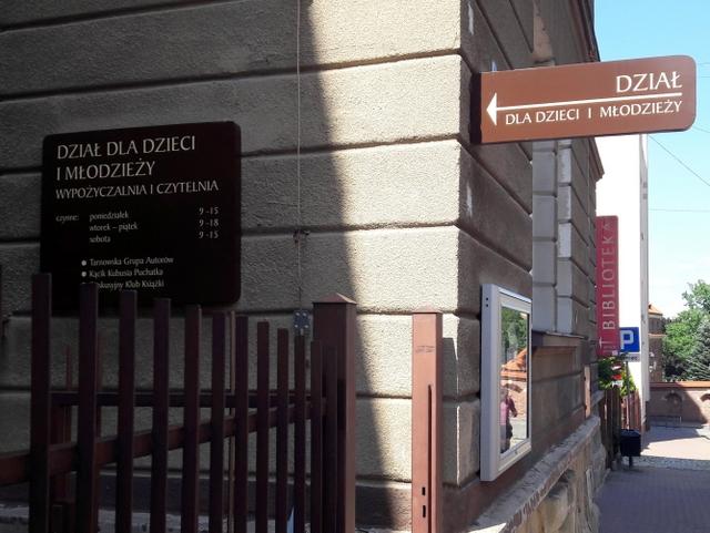 Fragment budynku z tablicami informacyjnycmi: Dział dla Dzieci i Młodzieży oraz Bilbioteka