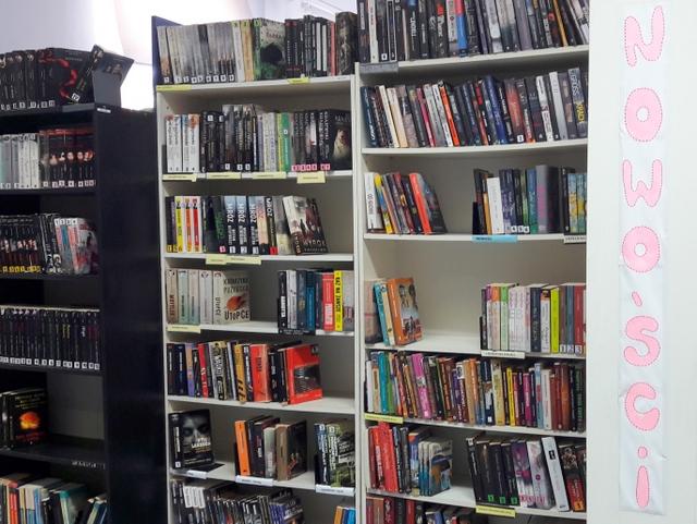 Regał z nowościami książkowymi. Z prawej strony napis: Nowości.