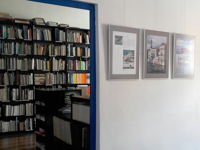Fragment wystawy fotograficznej. Przez otwarte drzwi widoczna pracownia z księgozbiorem.