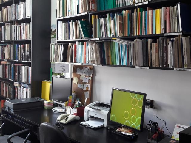 Stanowiska pracy z monitorami komputerowymi i półki z książkami.