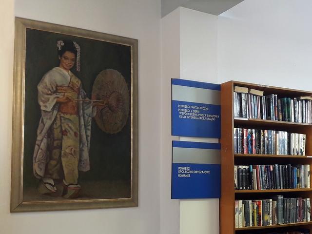 Fragment regałów w książkami oraz obraz przedstawiający Japonkę autorstwa Stanisława Westwalewicza