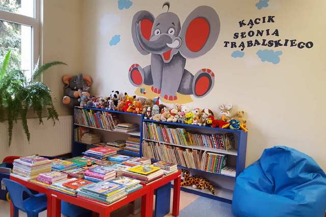 Kącik dla dzieci z namalowanym na ścianie słoniem, kolorowymi książkami i pluszakami