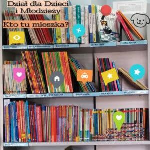 Regał z książkami. W lewym rogu napis Dział dla Dzieci i Młodzieży "Kto tu mieszka". Na książkach kolorowe ikonki-podpowiedzi.