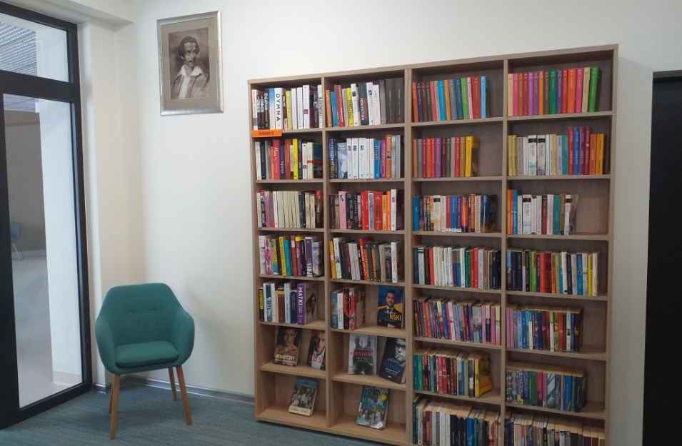 Regał z książkami, obok fotel i obraz z wizerunkiem Julisza Słowackiego