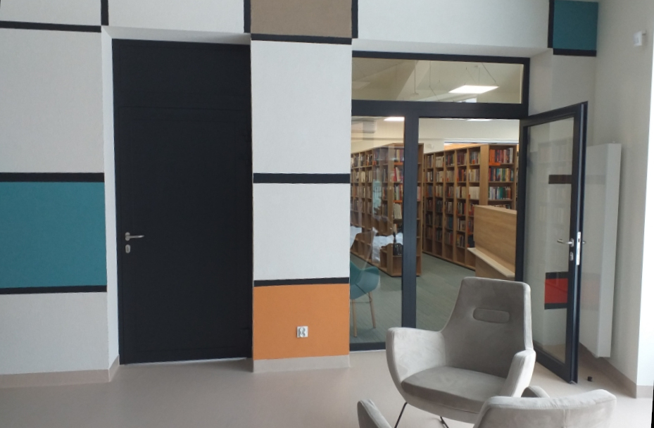 Przeszklone drzwi prowadzące do biblioteki. W głębi widoczne regały z książkami