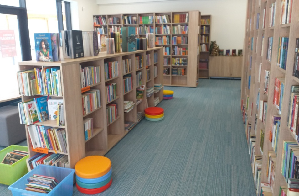 Wnętrze biblioteki z regałami na książki i kolorowymi siedziskami dla dzieci