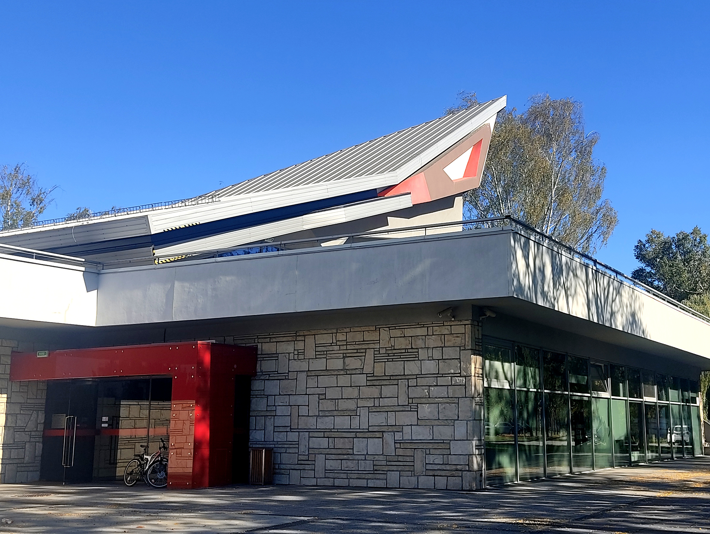 Obramowane na czerwono wejście do parterowego nowoczesnego budynku.