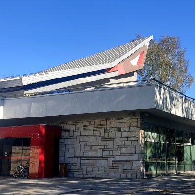 Obramowane na czerwono wejście do parterowego nowoczesnego budynku.