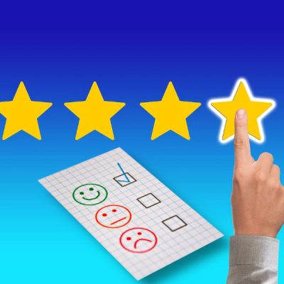 Na cieniowanym tle dłoń wskazująca czwartą gwiazdkę. Pod spodem fragment kartki z trzema ikonami uśmiechniętej obojętnej i niezadowolonej "buźki". Odznaczona pierwsza ikona.